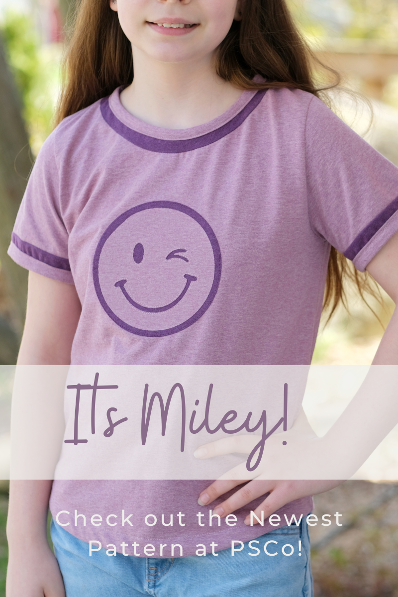 Child wearing a custom sewn Miley t-shirt featuring a wink face appliqué in coordinating colors, with a title reading